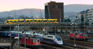 Tango überquert die Gleise des Bahnhofs Basel SBB, wo gerade ein TGV 2N2 (Euroduplex) aus Zürich ankommt.