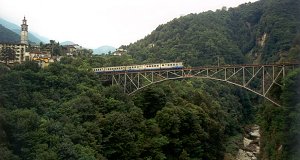 A train (ABe 8/8 with two cars) is crossing the Isorno-viaduct toward Locarno, near Intragna