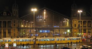 The building of Nyugati station in night lights, with a tram