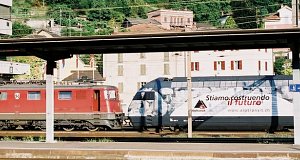 Electric locomotive Ae 6/6 11470 is standing at the station with the Ref 460 118 advertising for AlpTransit
