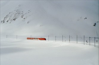A Glacier Express kétkocsis első része érkezik a befagyott és behavazott tó partján...